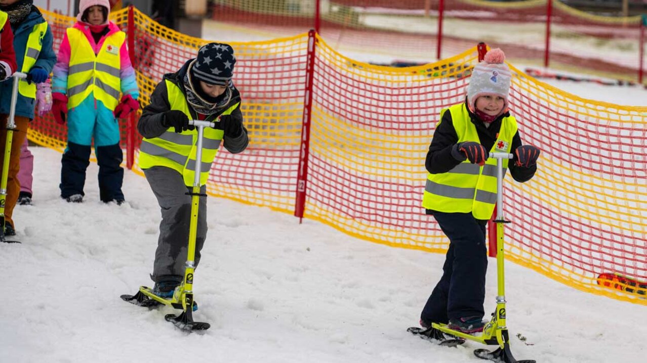 Kinder liefern sich Wettrennen auf Schnee-Tretrollern | © Albert Reiter