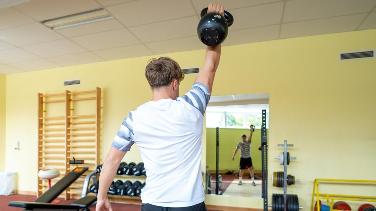 Athlet beim einarmigen Stemmen eines Dumbbells | © Albert Reiter