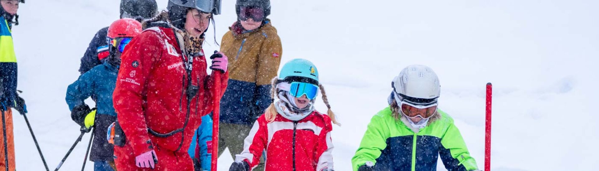 Kinder stehen neben Skitrainerin am Start eines Rennkurses, bekommen Tipps | © Albert Reiter