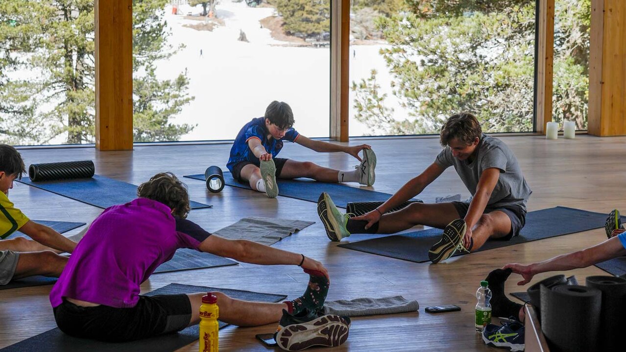 Athleten sitzen am Boden im Kreis, machen Lockerungsübungen | © Albert Reiter